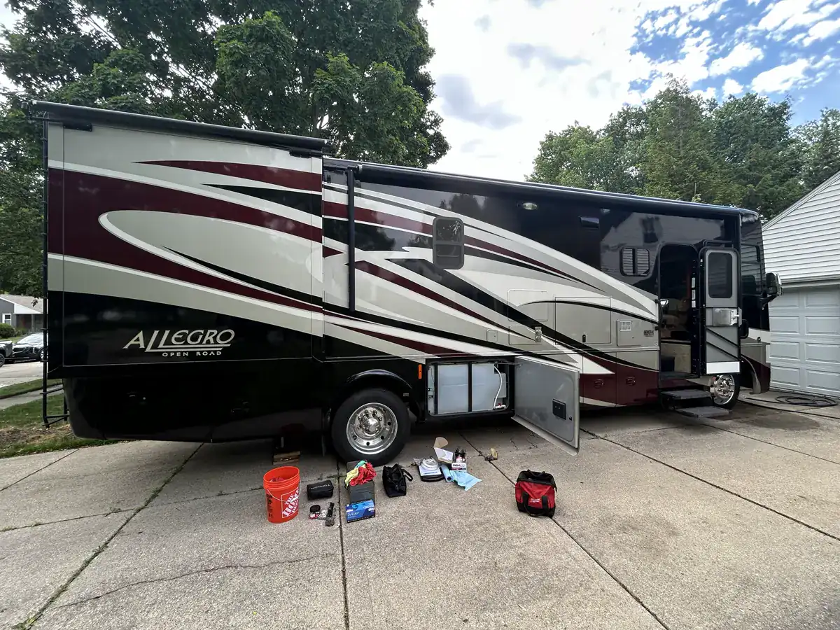 Tiffin Allegro Open Road motorhome on a residential driveway with tools beside an open service bay.