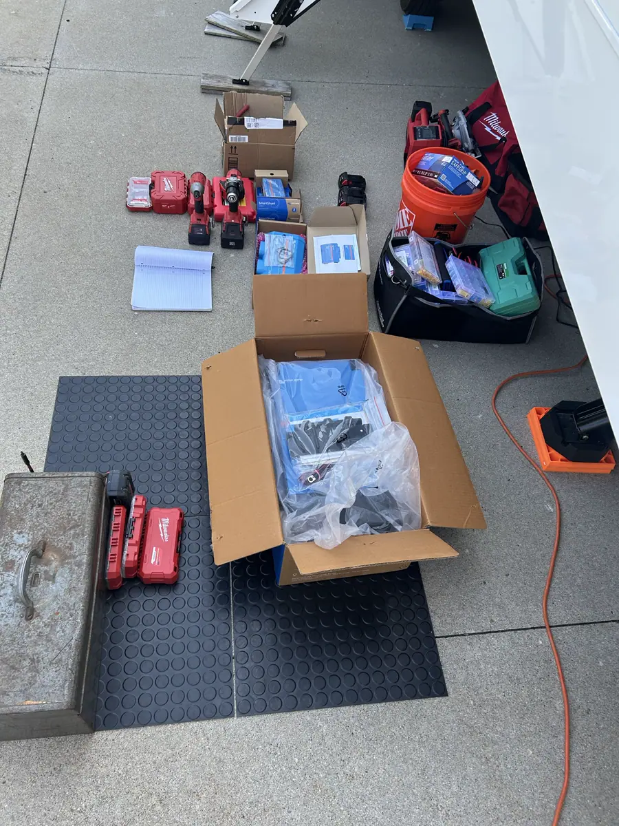 Milwaukee tools and Victron Energy components laid out on a driveway next to an RV for a mobile electrical installation.